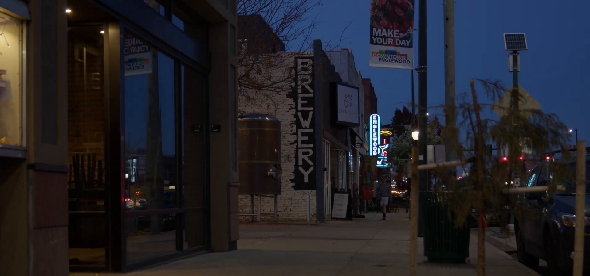 Brewability's shopfront on South Broadway at dusk, with a lit vertical BREWERY sign and street banners along the pavement.