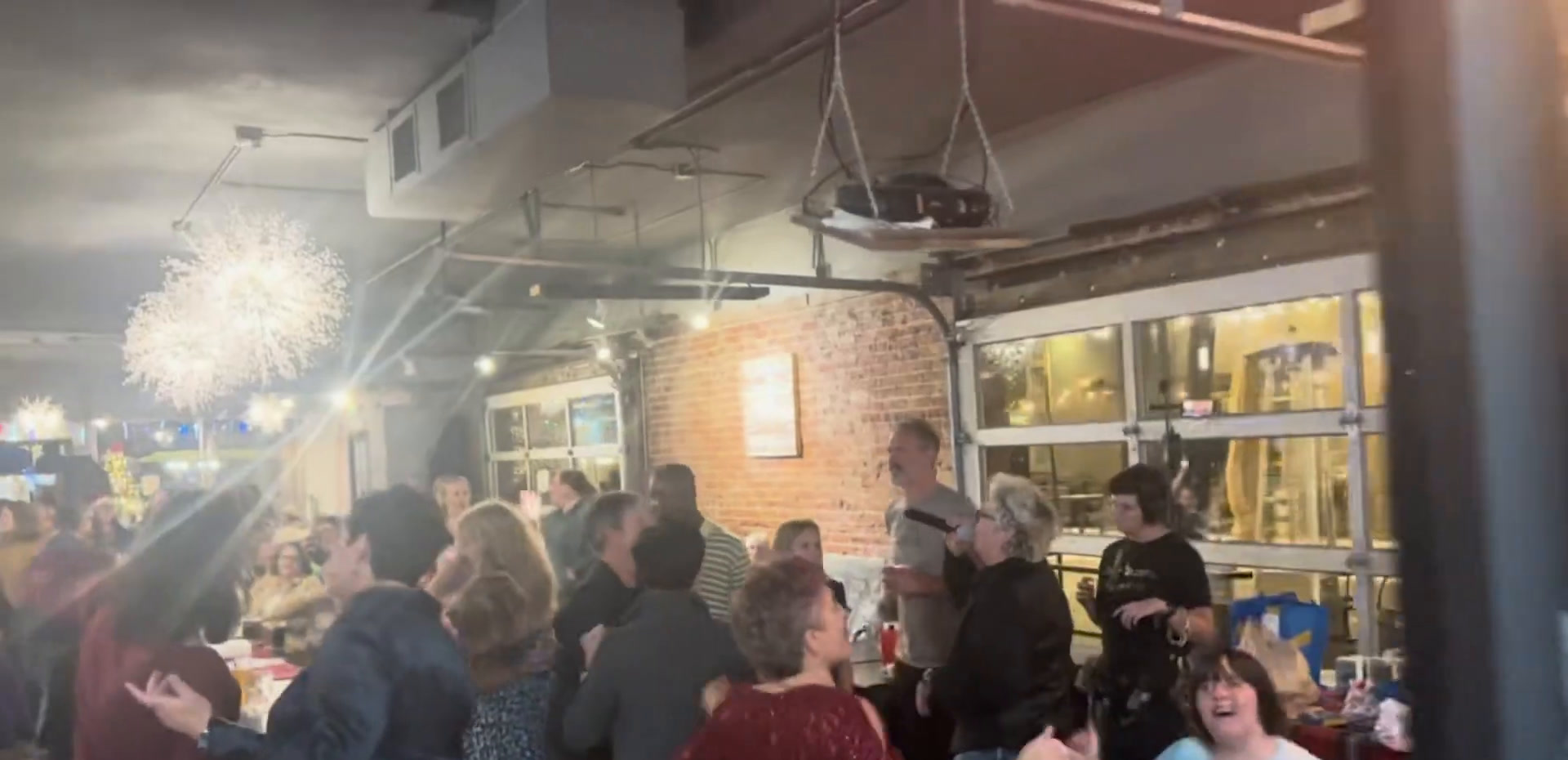 A busy evening at Brewability with people dancing and standing together under colored lights.