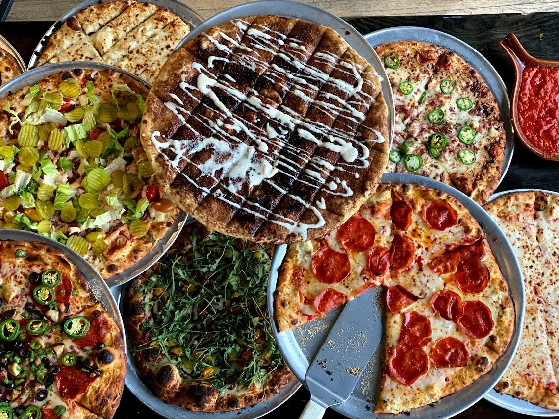 A spread of Brewability pizzas with a variety of savory toppings and a cinnamon dessert pizza.