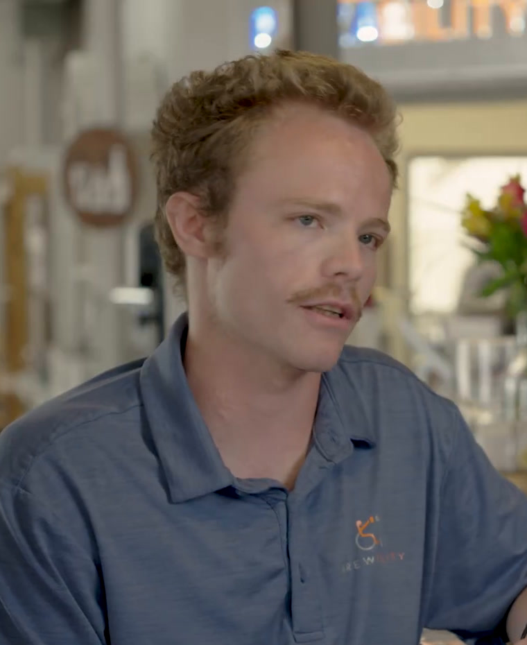 Avery in a blue Brewability polo shirt at the bar.