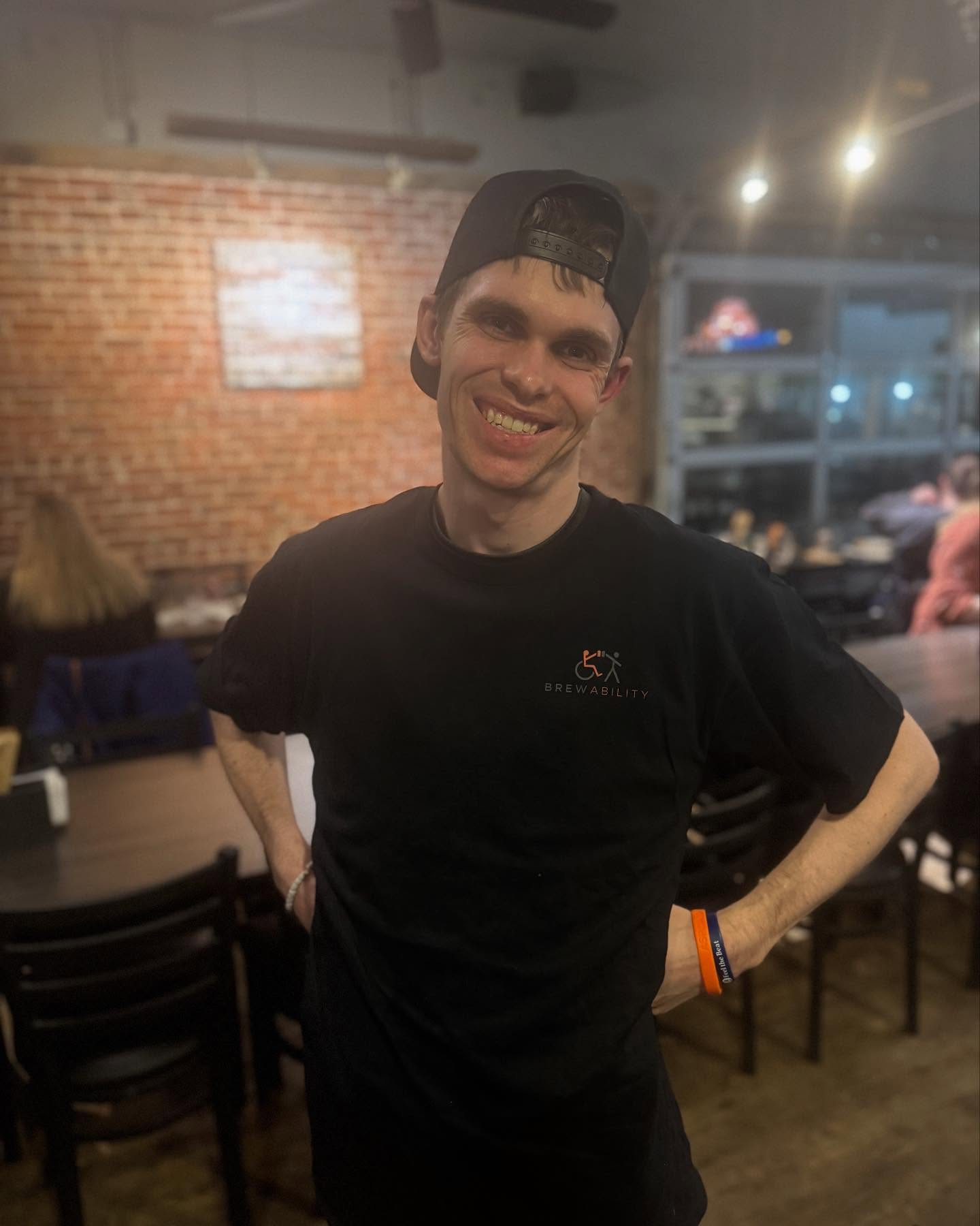 Charlie smiling in a black Brewability shirt and backward baseball cap inside the dining room.