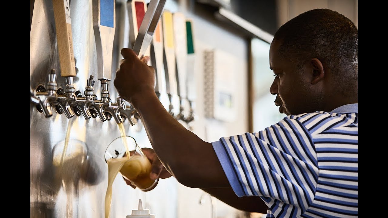 Aaron carrying a rack of glassware through the Brewability bar.